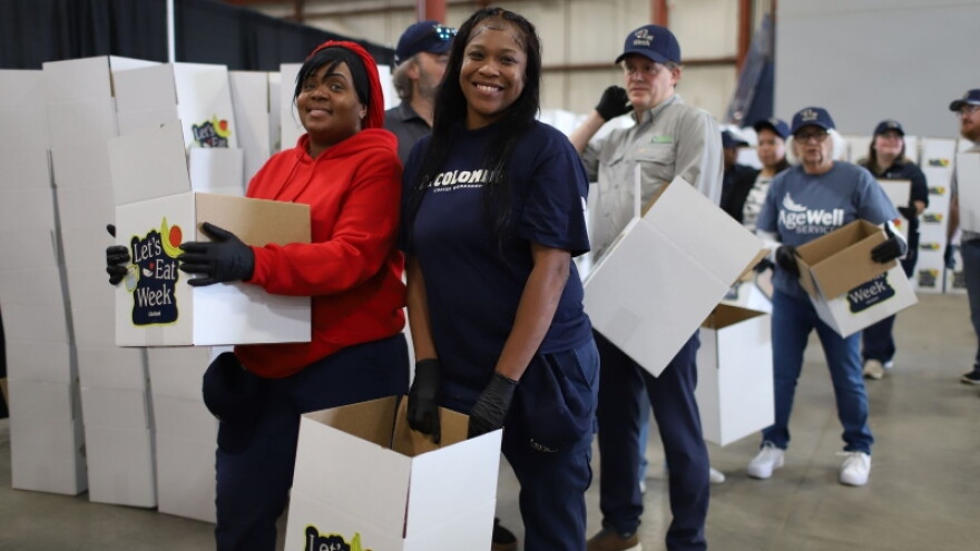 Employees and volunteers pack food donations boxes at Chobani's LaColombe facility in Norton Shores