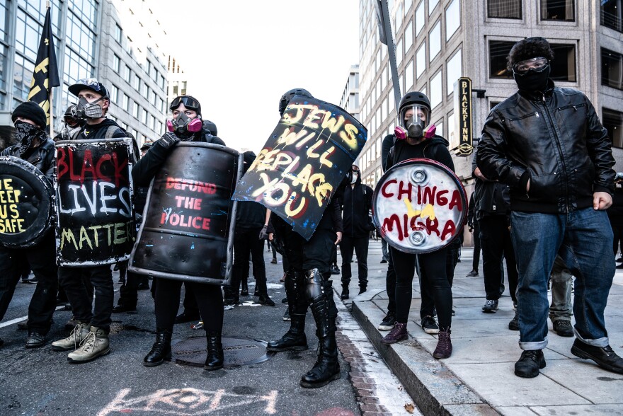 Counterprotesters form a line behind a police line while chanting, "Whose streets? Our streets," to the Proud Boys, who are on the opposite side chanting, "F*** antifa."