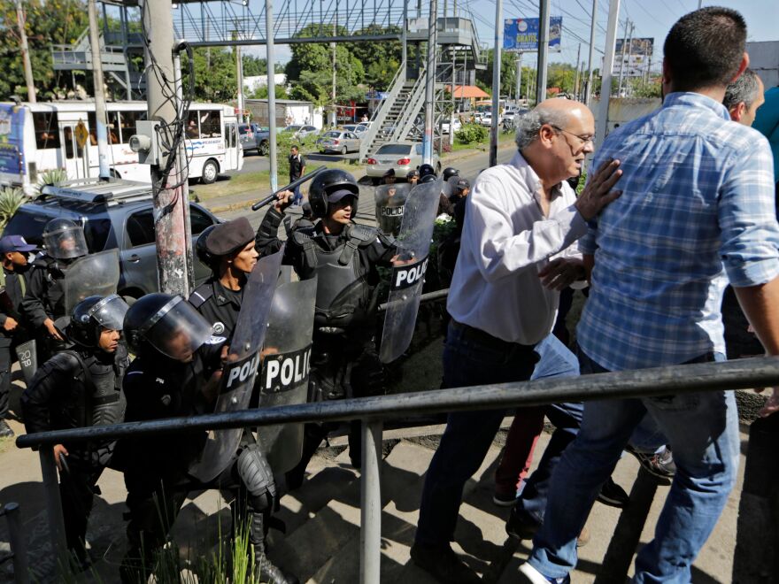 Nicaraguan riot police clear journalists, including Carlos Fernando Chamorro (center), from outside a police station as he tried to speak to the National Police Senior Commissioner Francisco Díaz in Managua, on Dec. 15. Nicaraguan police occupied the headquarters of Chamorro's news organization<em> </em>and of civil and human rights groups.