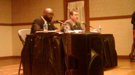 Challenger Darryle Buchanan (left) takes notes as incumbent Dayne walling talks during a mayoral debate Tuesday night in Flint