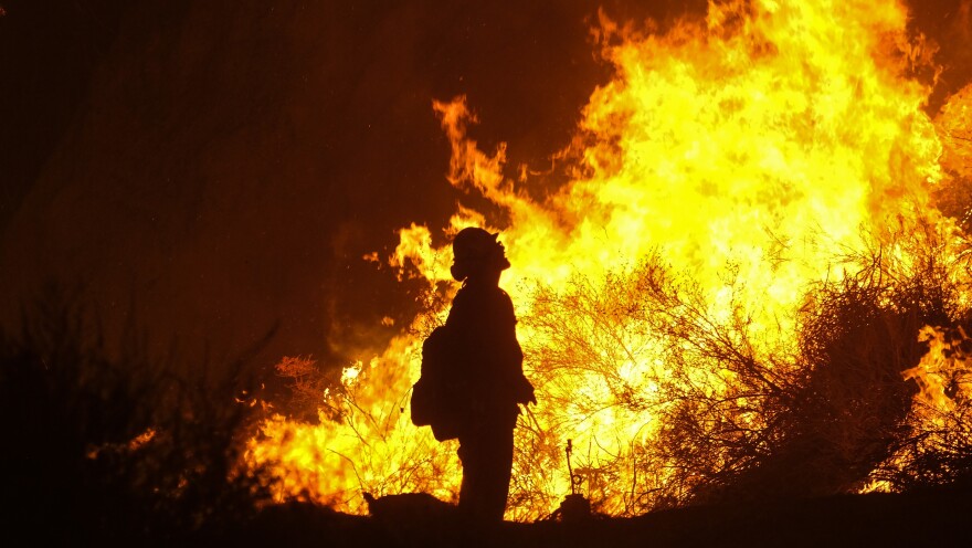 A firefighter looks on as the Holy Fire consumes a hillside Thursday in Temescal Valley in Corona, Calif.