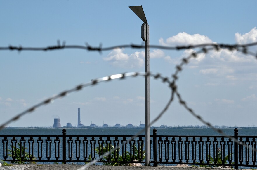 The Zaporizhzhia nuclear power plant in Ukraine's Enerhodar, Zaporizhzhia region, is seen through barbed wire on the embankment in Nikopol, Dnipropetrovsk region, central Ukraine, on July 20. Russian soldiers have been shelling Nikopol from the premises of the nuclear power plant.