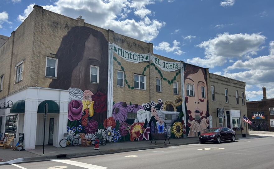 A mural on the side of a brick building featuring two women's faces and many flowers