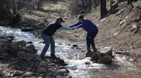 Case worker Diego Rivera helps lawyer Antonia Roybal-Mack across a waterway that used to be a road
