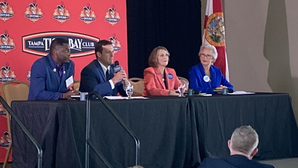 Four people sitting at a dais on a stage