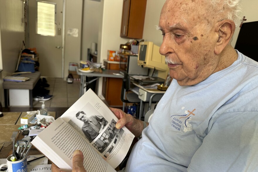 Jim Becker, a former Associated Press journalist, holds a book showing a 1945 photo of him as a Stars and Stripes correspondent in Shanghai, at his home in Kāneʻohe, Hawaiʻi, May 21, 2024. (AP Photo/Audrey McAvoy)