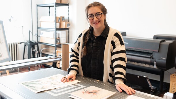 Joëlle Diane stands in her Akron studio with her printed artwork spread out on the table.