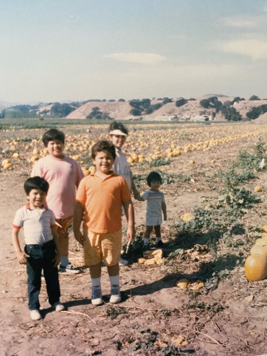 A young Carnegie Cellars Chef Steven Lara holds his mother's hand. His brothers are in the foreground.
