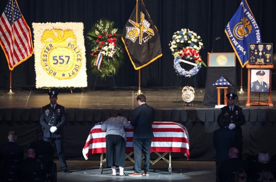 Lynn Mazurkiewicz kisses the casket of her husband, Rochester Police Officer Anthony Mazurkiewicz, after his funeral.