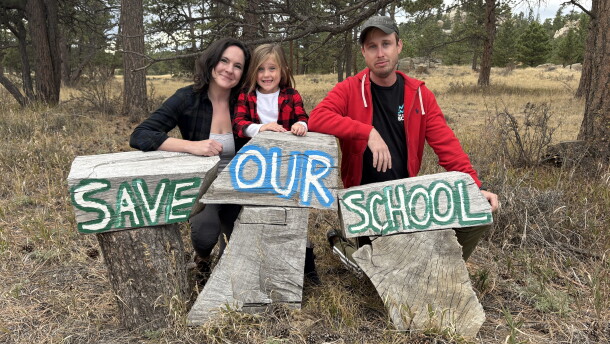 Three people lean against three pieces of wood, with the words "Save Our School."