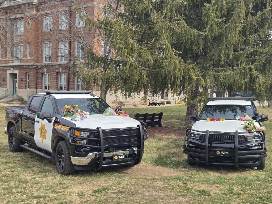 Two cruisers parked on the Christian County Courthouse lawn as memorials to Deputies Ramirez and Hislope.