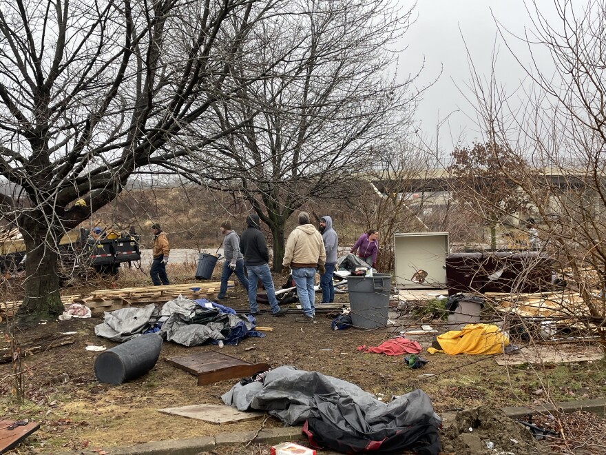 Employees from Akron's neighborhood assistance department gather as a waste management company disposes of belongings from an encampment on Dec. 7, 2022.