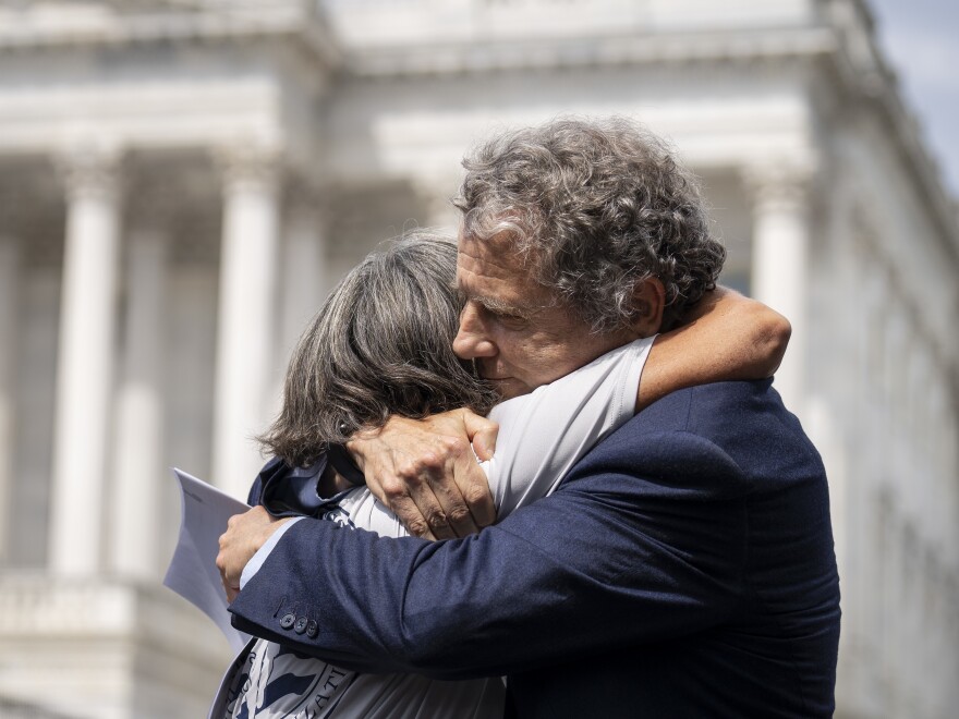 Susan Zeier, mother-in-law of the late Sgt. First Class Heath Robinson, hugs Sen. Sherrod Brown (D-Ohio) during Thursday's news conference.