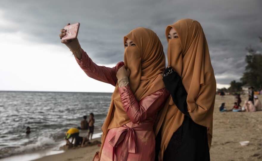 Women take a selfie on the Muslim holiday of Eid al-Fitr on Thailand's Talo Kapo beach.