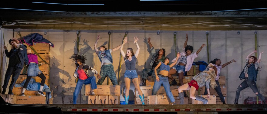Scene from Carmen where a bunch of women are dancing with their arms in the air.