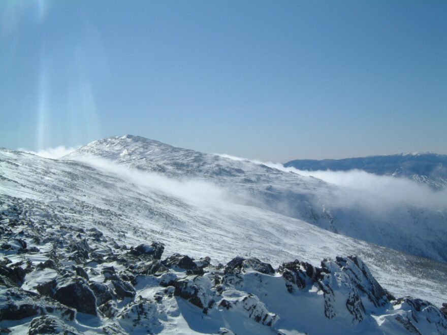 Snow being moved by fierce winds to accumulate on the leeward side of the mountain.