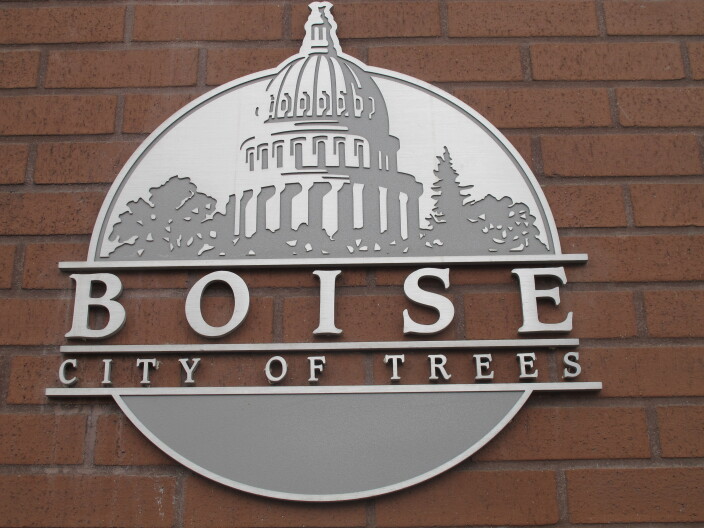 City of Boise logo featuring the Capitol, building with trees on either side and the words Boise City of Trees on a red brick background.