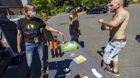 Tapestry Health nurse Katy Robbins hands bottles of water to Kyle as he visits the harm reduction mobile unit at Energy Park in Greenfield. (Jesse Costa/WBUR)
