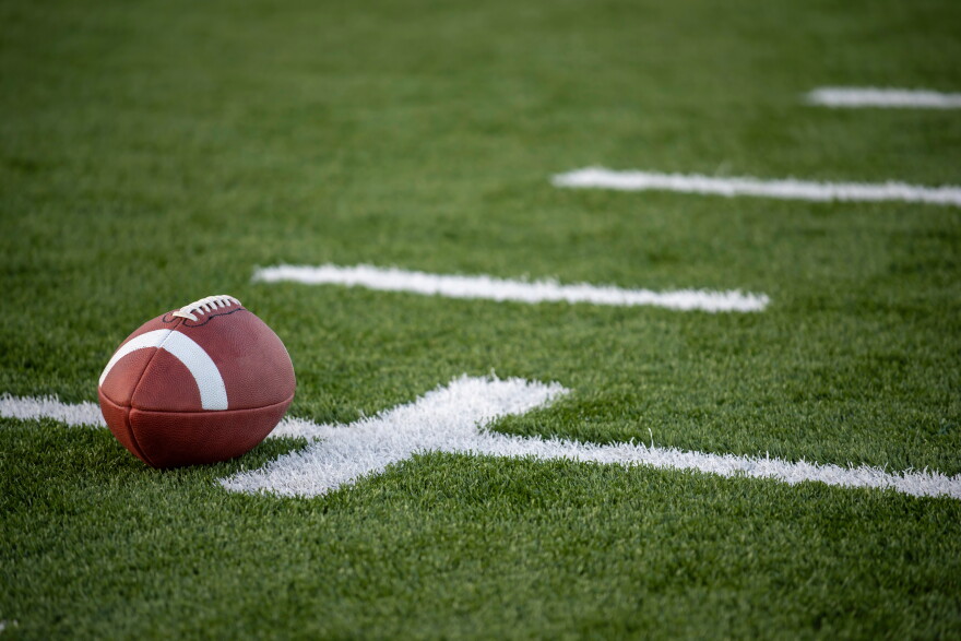 A brown leather american football on a green playing field