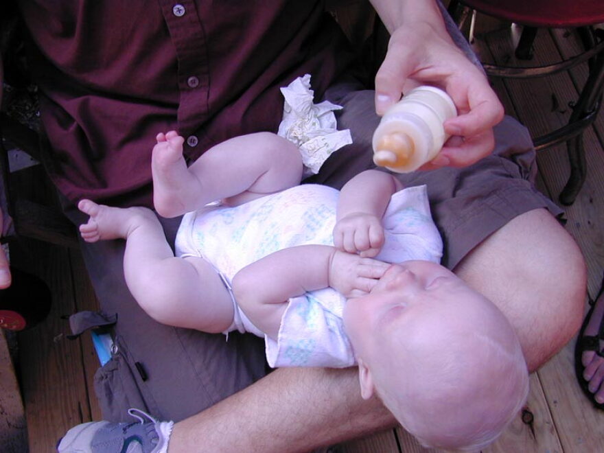  An infant drinks from a bottle.