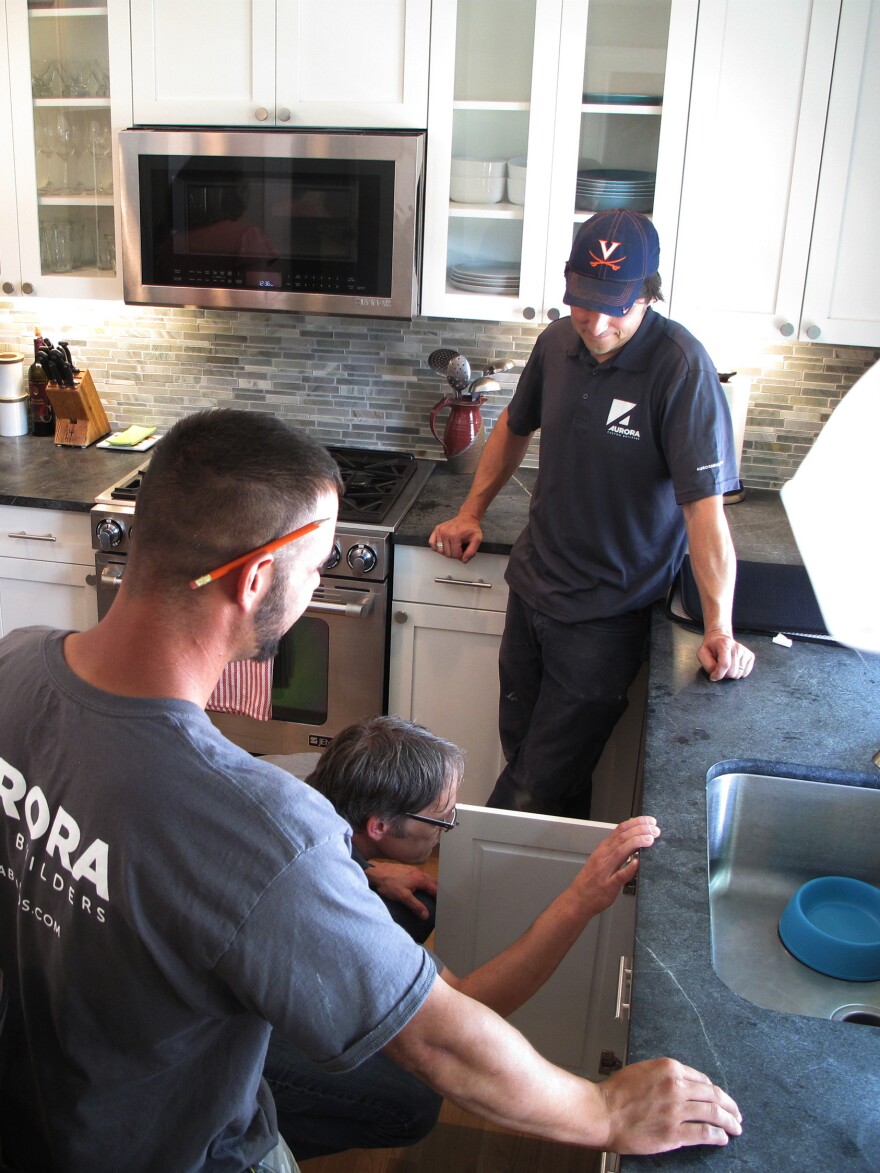 Nathaniel May (under sink) and his crew with Aurora Custom Builders goes through the final check list on a kitchen renovation outside Boston.