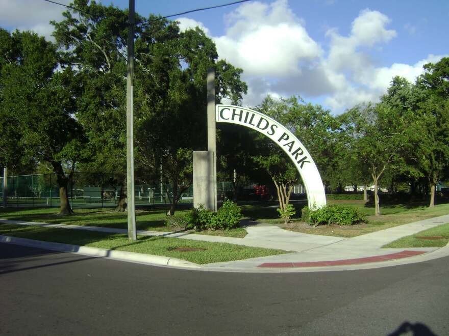 Entrance of the park, with many trees around and a circular concrete frame that says "childs park."