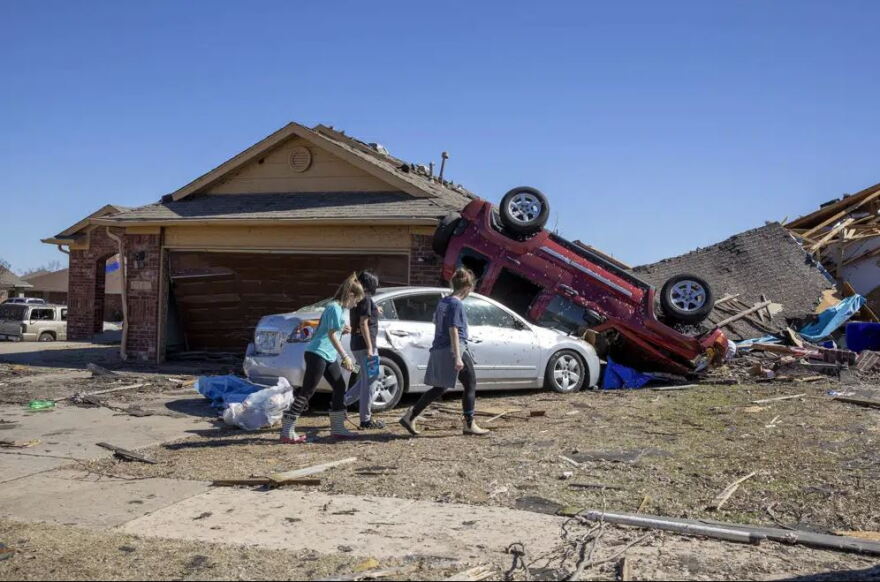 Neighbors walk in front of a home damaged at Wheatland Drive and Conway Drive on Monday, Feb. 27, 2023 in Norman, Okla. The damage came after rare severe storms and tornadoes moved through Oklahoma overnight.