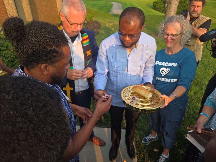 Springfield Haitian Support Center Executive Director Viles Dorsainvil, Pastor Carl Ruby and others administer communion to Haitians entering ICE's Blue Ash field office for immigration appointments Sunday, Aug. 9, 2026.