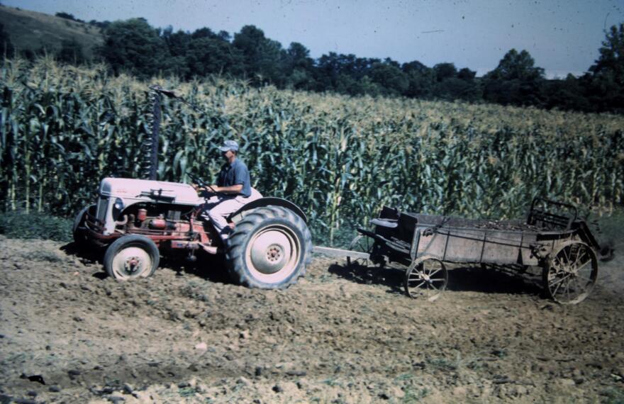 A tractor pulls a manure spreader in 1952.