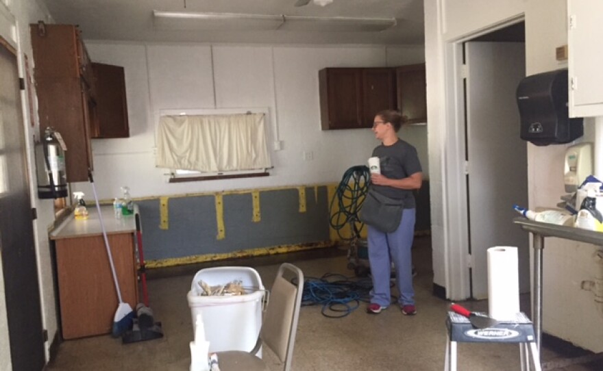 Former kitchen at Tri-Lakes banquet hall with a woman showing an area that will be converted for laundry.