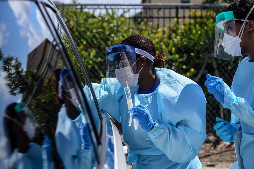 Medical personnel take patient samples at a drive-through coronavirus testing site in West Palm Beach, Florida, Monday, March 16, 2020.