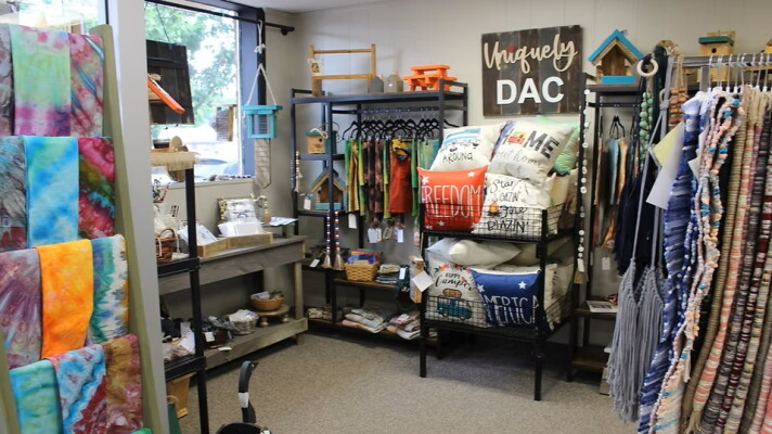 A cozy corner of a thrift store with tie-dyed items, handmade rugs, pillows and more. 