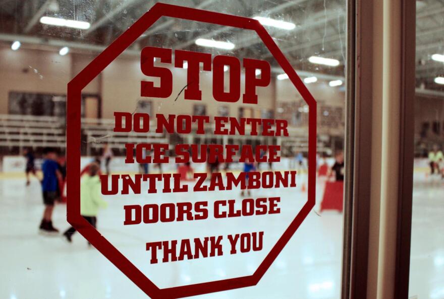 A sign warns skaters to remain off the rink until the Zamboni doors have fully closed.