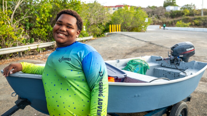 Jadriel John, better known as “JJ,” stands next to his 9-foot fiberglass dinghy on August 16 at Altona Lagoon.