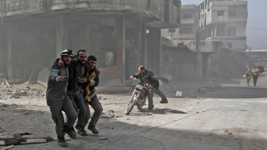 Volunteers from the Syrian Civil Defense, often known as the White Helmets, help an injured man in Hamouria during Syrian government shelling earlier this month.
