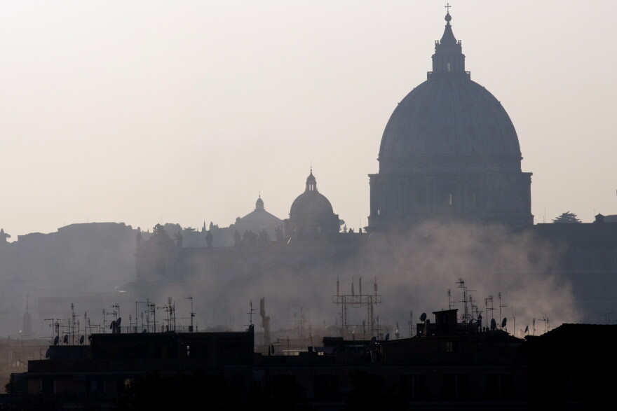FILE - In this Dec. 23, 2015 file photo, smoke billows from chimneys in central Rome, in front of St. Peters's Basilica dome. Local authorities have been restricting car use following high air pollution levels. (AP Photo/Alessandra Tarantino)