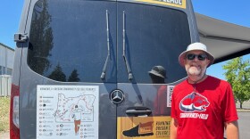 A man stands near the back of a parked van.