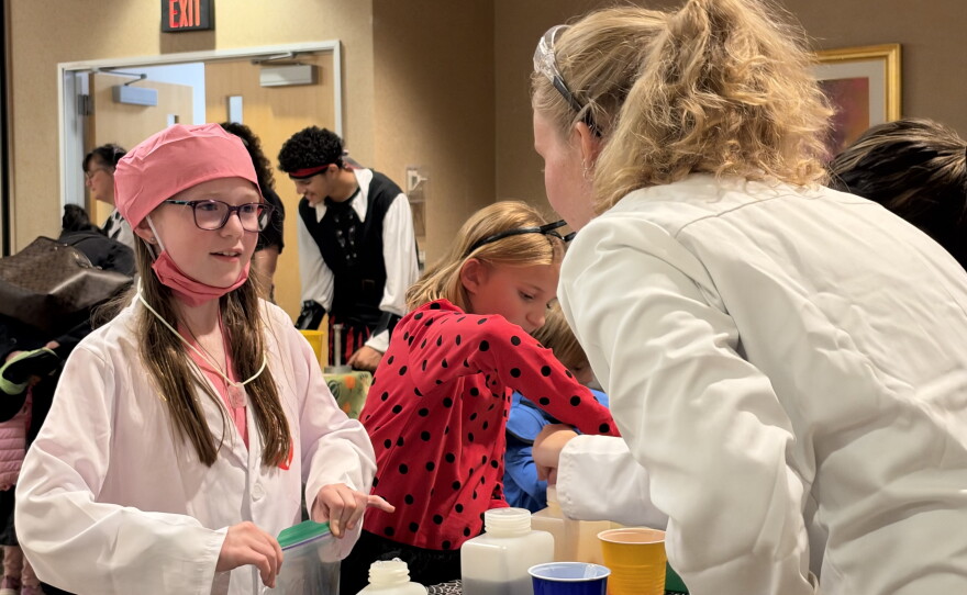 Olivia Blaum, 10, of Bear Creek, dressed as a nurse, completes a hands-on science activityyLaura Nemeth, a third-year pre-professional physician assistant student at King's College, helps Olivia Blaum, 10, of Bear Creek, with a hands-on science activity.