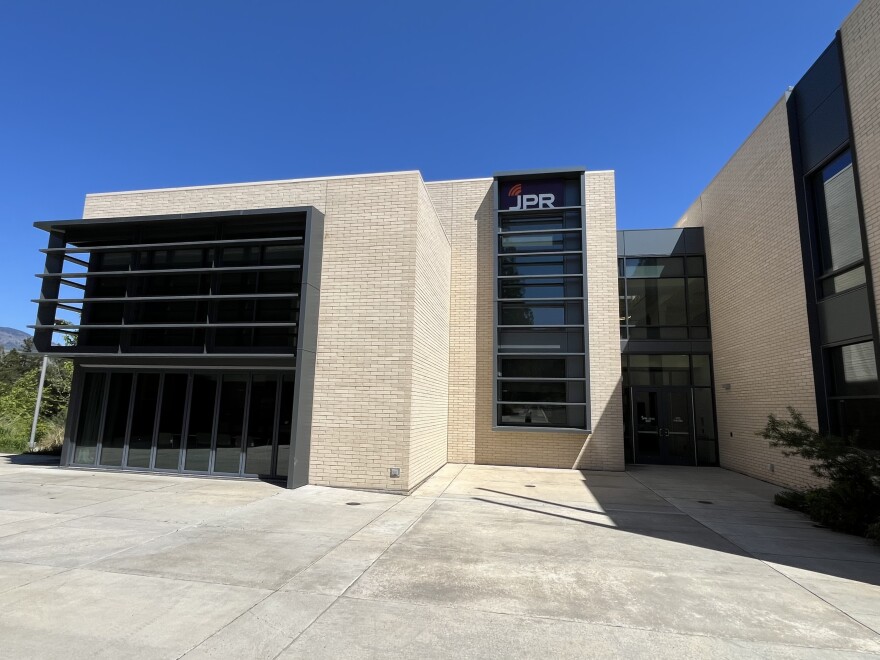 A two-story pale brick building with metal trim on the windows. 