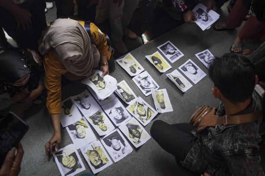 People looking for their family members inspect photographs of victims provided by volunteers to help them identify their relatives in Malang, East Java, Indonesia, on Sunday.