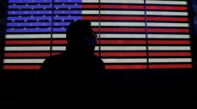 A person walks by an illuminated LED billboard of a US Flag in Times Square, New York.