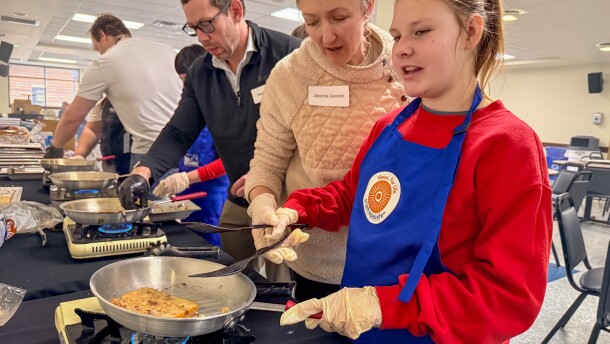 A volunteer helps Carley Zagalik prepare french toast.