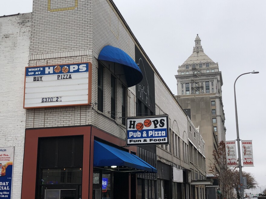 Signs for Hoops Pub & Pizza are mounted on the side exterior wall and above the entryway at 516 Main Street in downtown Peoria. 