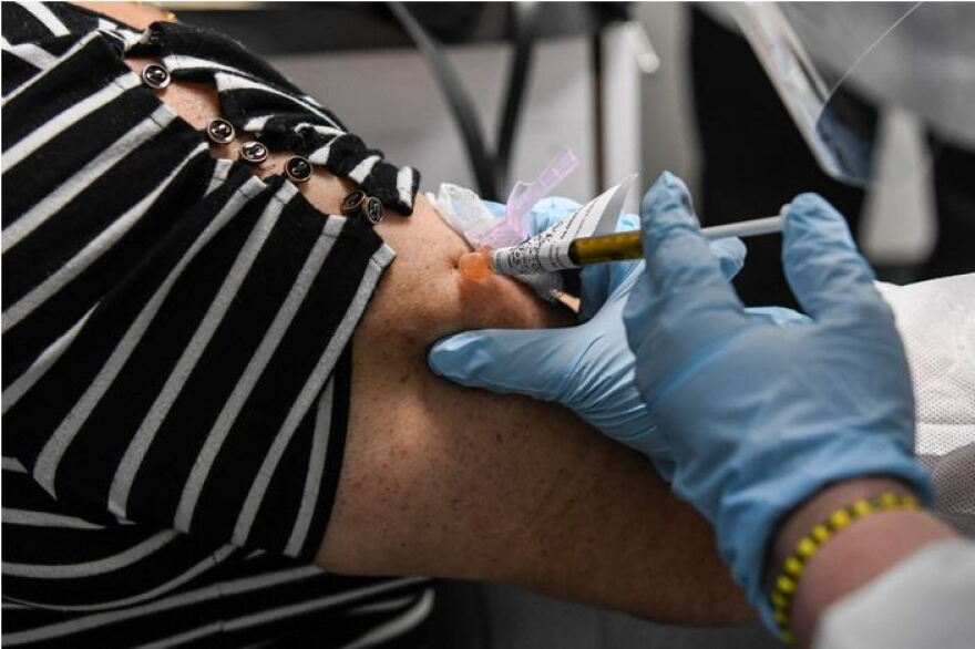 COVID-19 vaccination needle is being inserted into an arm