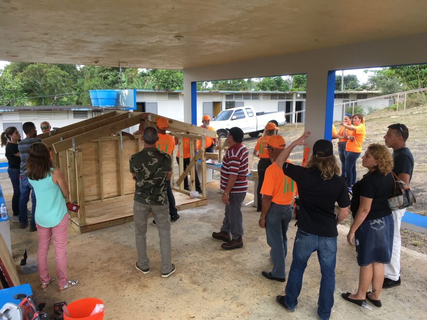 Workshop participants review the construction of a hurricane-resistant model house they built.