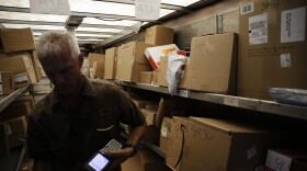 Boxes sit on the truck as UPS driver Marty Thompson registers a delivery. (David Goldman/AP)
