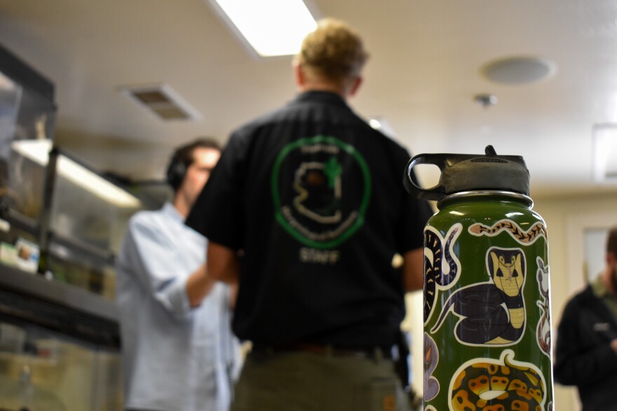 Water bottle with reptile stickers with people talking behind