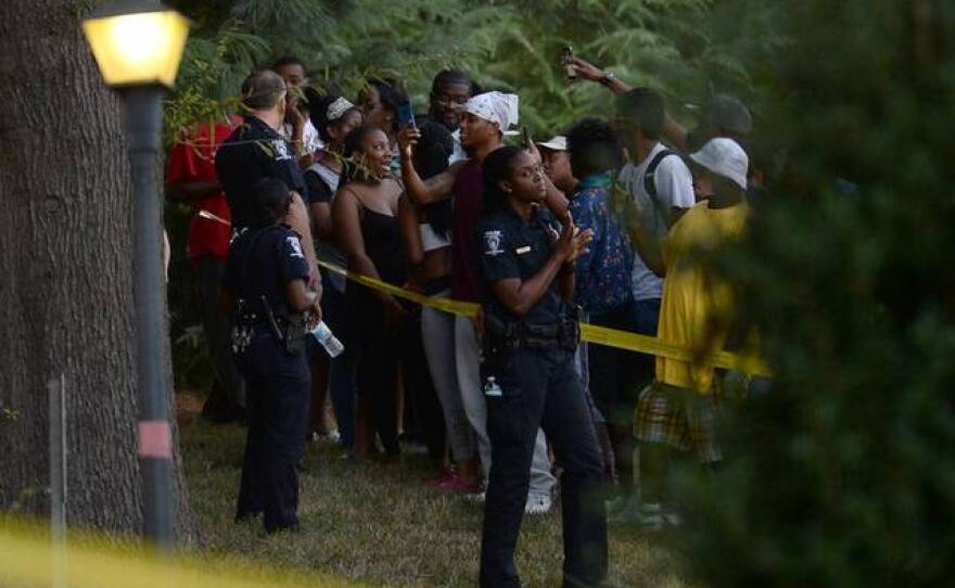 People gather on a hill as Charlotte police work the scene at The Village at College Downs apartments on Tuesday, September 20, 2016.