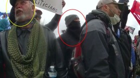Screenshot of body worn camera footage showing Matthew Huttle (circled in red) facing police officers as his co-defendant (circled in yellow) berates police officers.