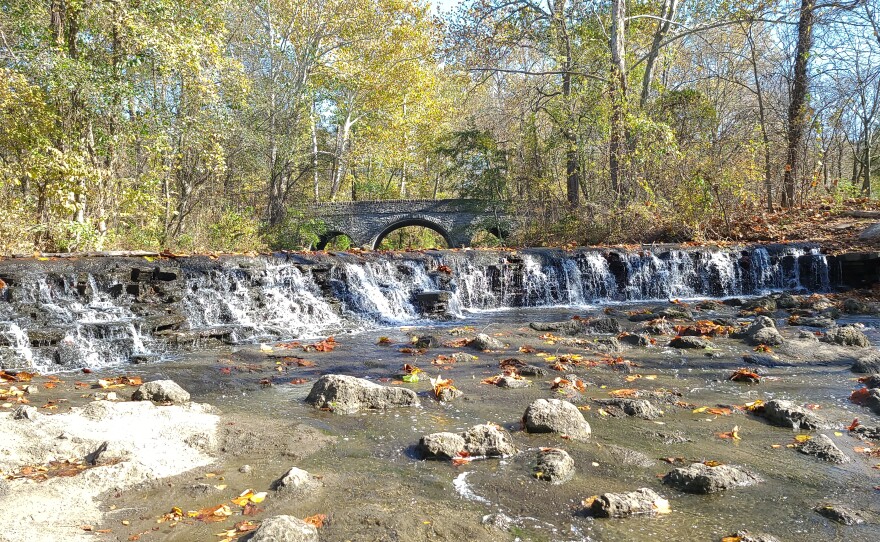 a waterfall with a stone bridge in the background